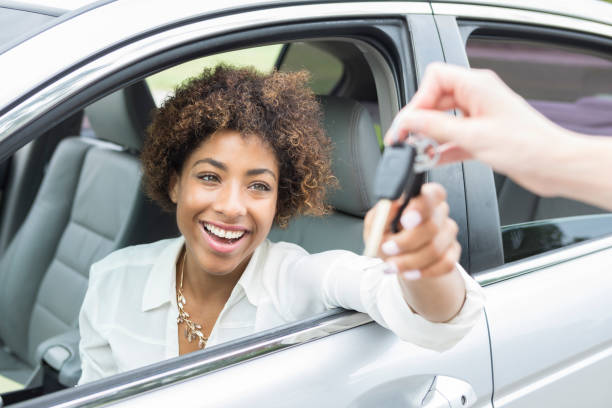 Jeune femme dans une voiture qui reçoit les clefs du véhicule en souriant