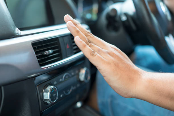 Main de femme devant le chauffage d'une voiture