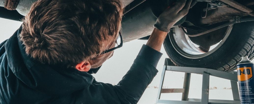 Homme qui est sous une voiture pour la réparer