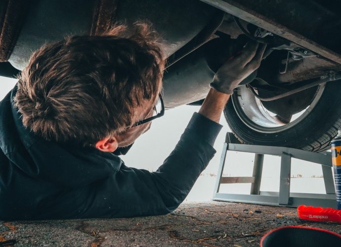 Homme qui est sous une voiture pour la réparer